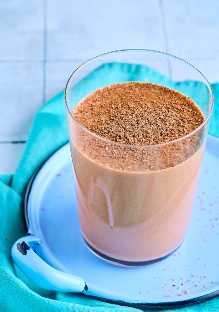 Bebida de chocolate servida en un vaso sobre un plato azul